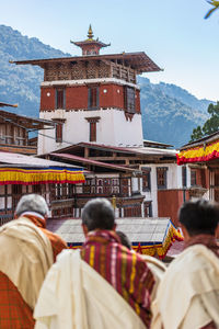 Rear view of people outside building against sky