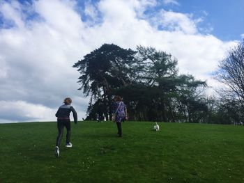 Rear view of mother and daughters with dog at park