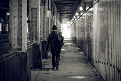 Rear view of man walking in illuminated tunnel