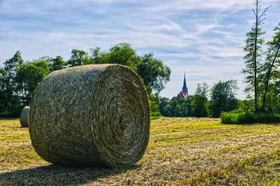 Hay bales on field against sky