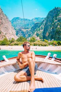 Shirtless man sitting in boat on sea