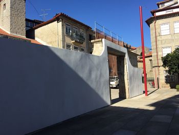 Street by buildings against sky on sunny day