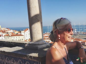 Smiling senior woman against cityscape and sea