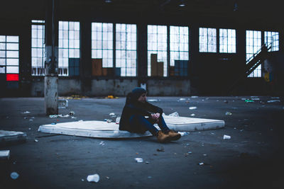 Man sitting on mattress in abandoned building