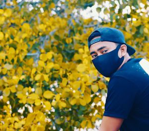 Portrait of young man standing on yellow flowering plants