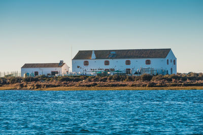 Houses by sea against clear sky