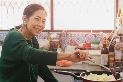 Senior woman cooking food on the stove in kitchen