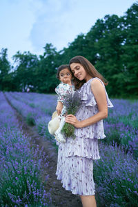 Full length of woman standing by purple flowering plants