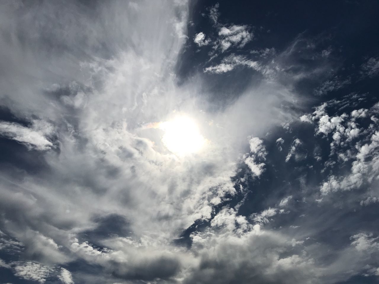 LOW ANGLE VIEW OF SUNLIGHT STREAMING THROUGH CLOUDS IN SKY