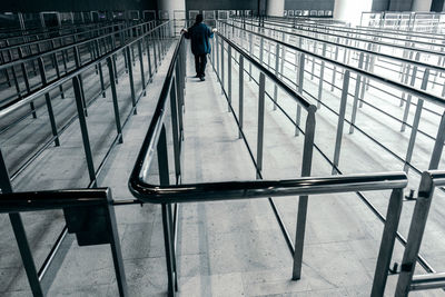 Rear view of man walking amongst an empty queue railings