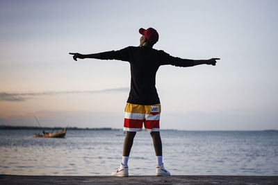 Full length rear view of man standing in sea against sky