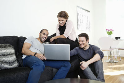 Cheerful multi ethnic friends sharing laptop