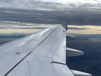 Airplane wing over clouds against sky