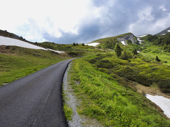 Road amidst green landscape against sky