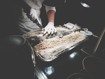 Midsection of chef cutting fish in restaurant kitchen