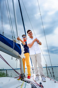 Two young man standing on a sailboat. summer vacations, cruise, recreation