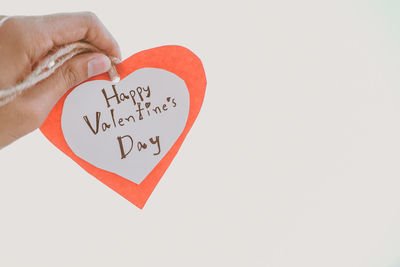 Close-up of hand holding heart shape over white background