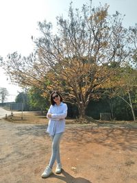 Portrait of young woman standing against tree