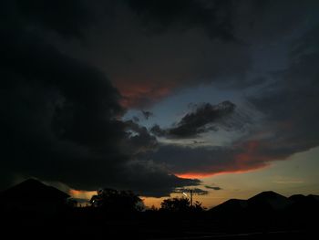 Silhouette trees against dramatic sky during sunset