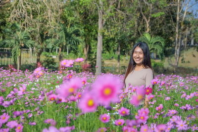 Portrait of smiling woman standing amidst flowers