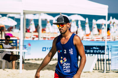 Young man wearing sunglasses standing on beach