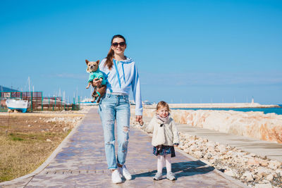 Full length portrait of young woman wearing sunglasses against sky