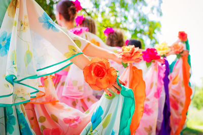 Bridesmaids in colorful clothing and roses standing outdoors