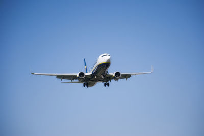 Low angle view of airplane flying against clear blue sky