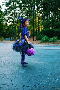 Full length of girl in costume standing on cobbled footpath