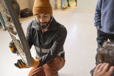 Male technician examining bicycle wheel at recycling center