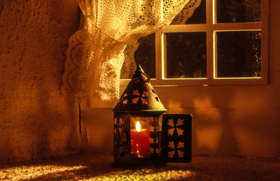 Close-up of lit candle against the window