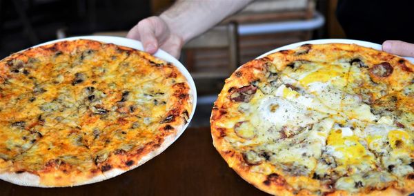 Close-up of hand holding pizza