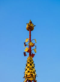 Low angle view of cross sculpture against blue sky