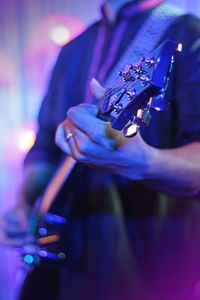 Midsection of man playing guitar during event