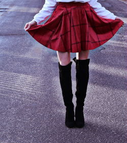 Low section of woman holding red skirt on road