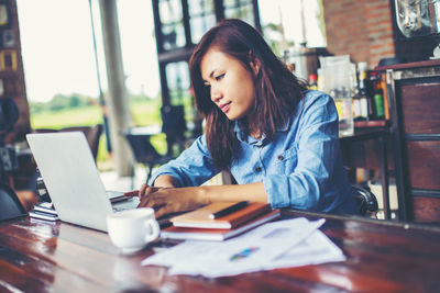 Young woman using phone while sitting on table