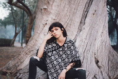 Young woman sitting on tree trunk