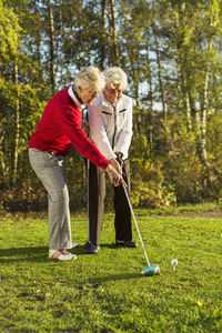 Full length of senior female friends playing golf