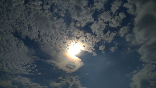 Low angle view of sunlight streaming through clouds