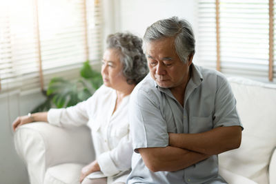 Unhappy senior couple sitting at home on sofa