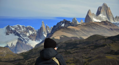 Rear view of woman standing on mountain against sky