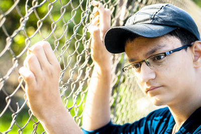 Close-up of thoughtful boy by fence