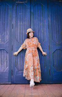 Portrait of woman standing against wooden wall