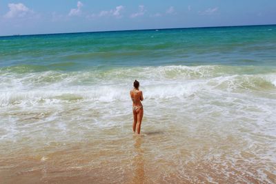 Rear view of shirtless man standing on beach