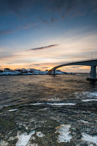 Bridge over river against sky during sunset