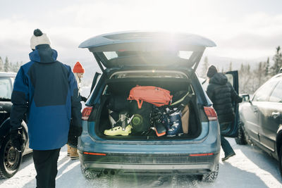 Rear view of people standing on car against sky