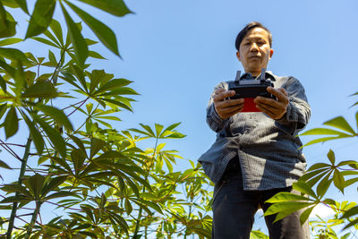 Low angle view of man photographing against sky