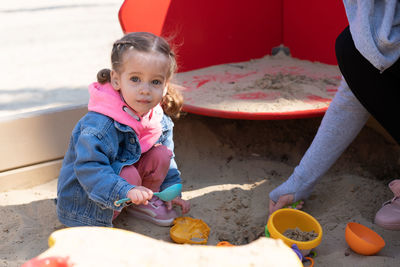 Full length portrait of cute girl playing while crouching on sand