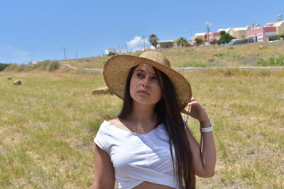 Portrait of young woman wearing hat on field