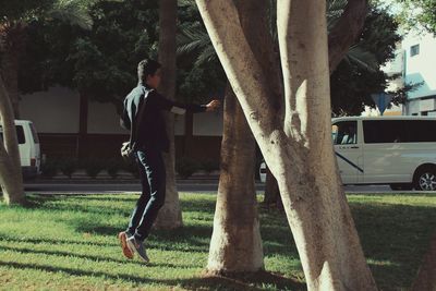 Man jumping by tree trunk at park